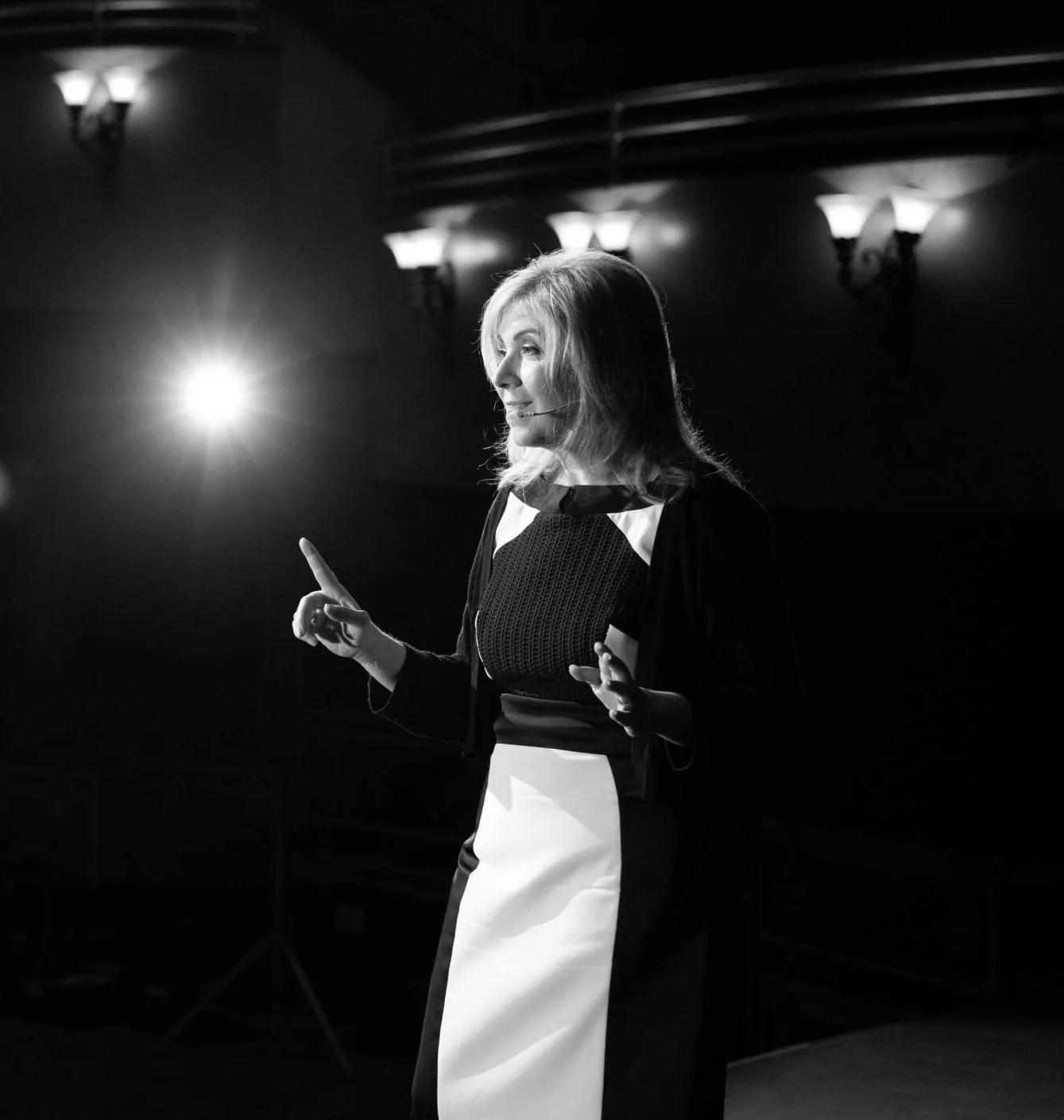 Leslie Zane speaking on a theatre stage under a spotlight